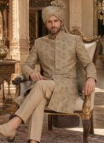 Seated groom in beige sherwani with matching turban, silk kurta pajama and beige-gold khussa