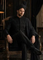 Seated groom in black embroidered sherwani with matching black turban and organza shawl