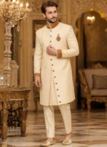 Full-length cream sherwani for groom with gold zari collar, cuff embroidery, chest motif and embellished buttons