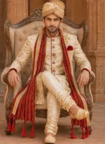 Ivory and gold groom sherwani styled with red shawl, ivory turban and matching khussa