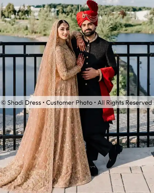 Real Shadi Dress bride wearing a heavily embroidered gold Pakistani bridal dress with her groom on their wedding day.