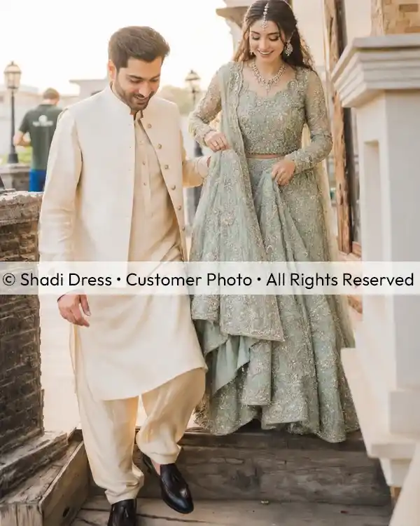 Real Shadi Dress bride wearing a sage green embroidered Pakistani bridal dress with her groom during a wedding celebration.