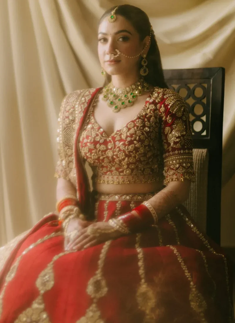 Ruby red wedding lehenga with antique gold embroidery, pendant motifs and graceful bridal styling