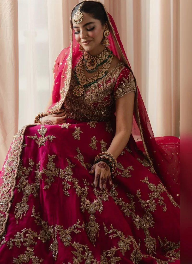 Fuchsia Pink Baraat Bridal Lehenga Choli with Gold Floral Embroidery – Front View Full front view of fuchsia pink Pakistani baraat bridal lehenga choli featuring heavy gold zari embroidery, floral arches, a flared silk skirt and matching dupatta.