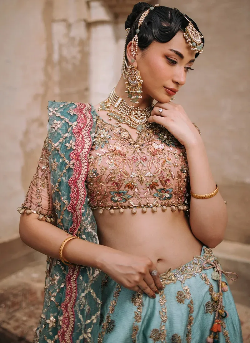 Aqua lehenga choli close-up with a blush floral embroidered blouse, notched neckline and dangling gold beads