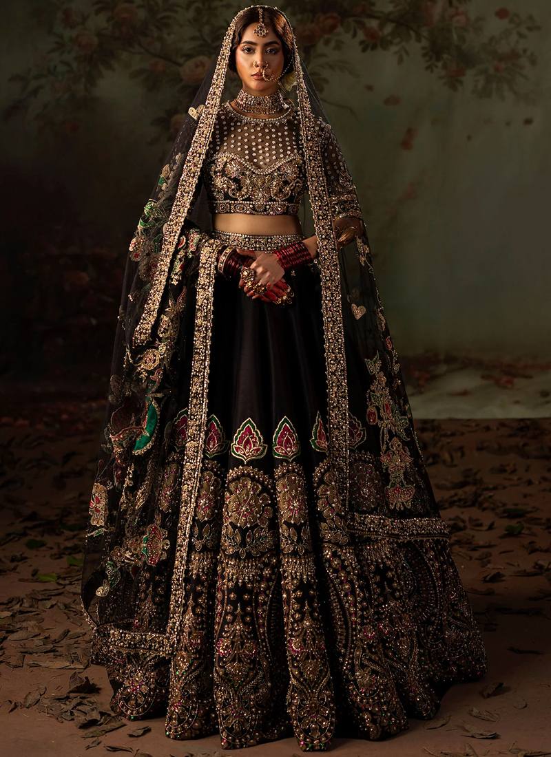 Black lehenga choli angled full-length view with sheer floral dupatta and ornate gold skirt panels