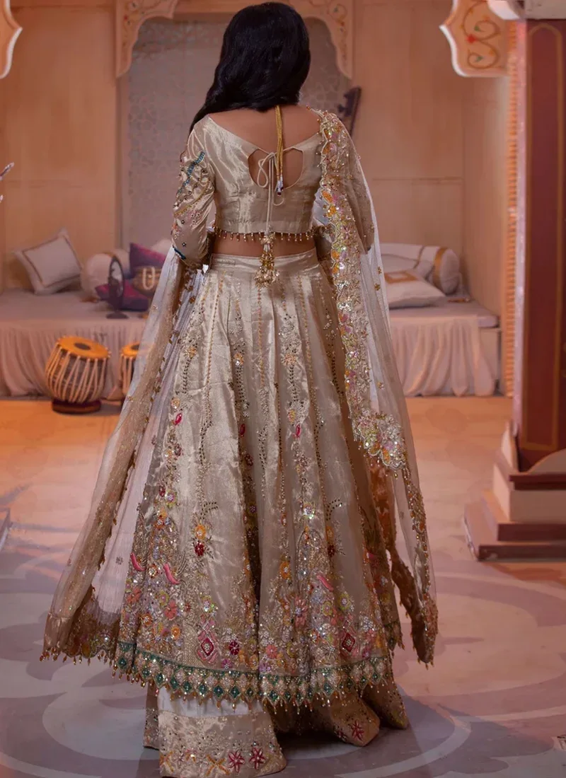 Champagne bridal lehenga choli, standing front view with a sheer floral-bordered dupatta and flared skirt.
