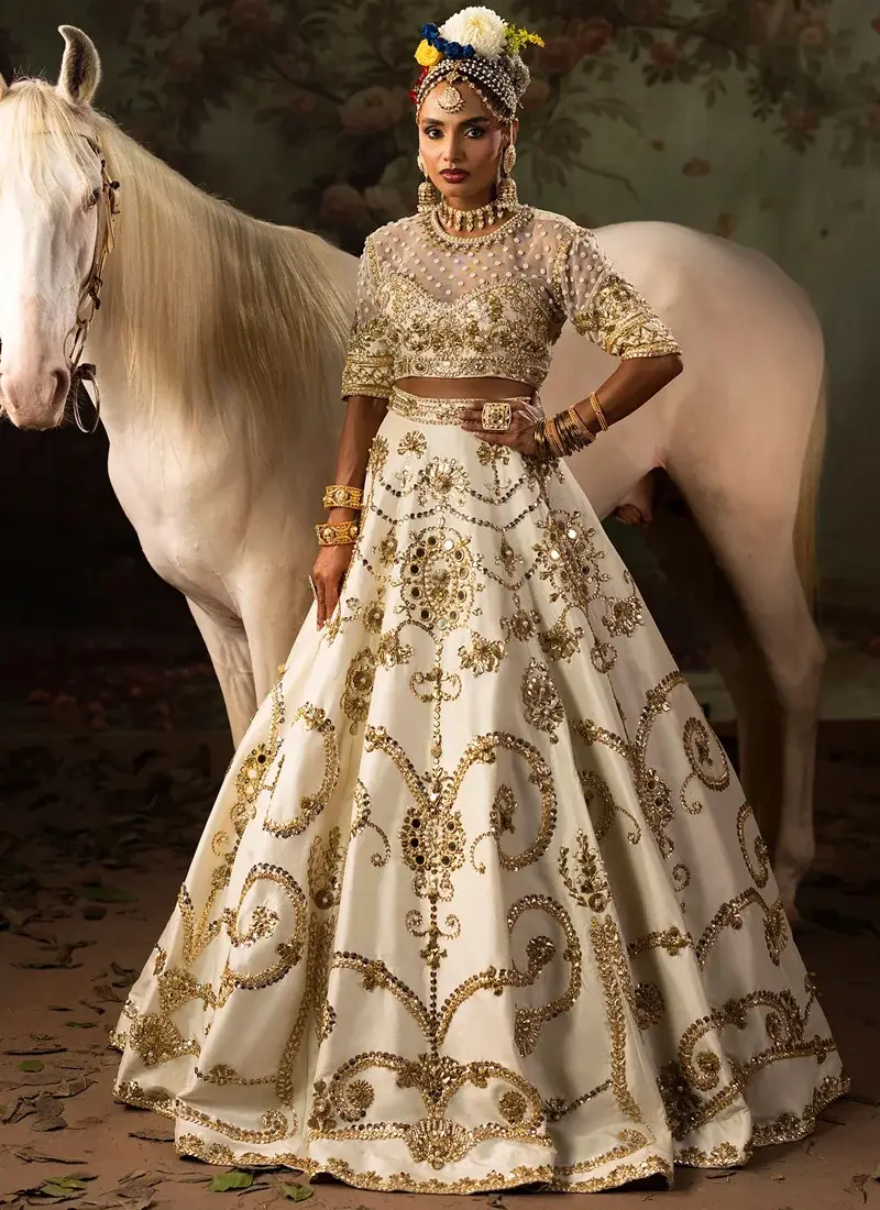 Ivory Walima Lehenga Choli with Gota Spiral Scrollwork Ivory lehenga choli in three-quarter front view with gold spiral embroidery and mirror-set floral motifs