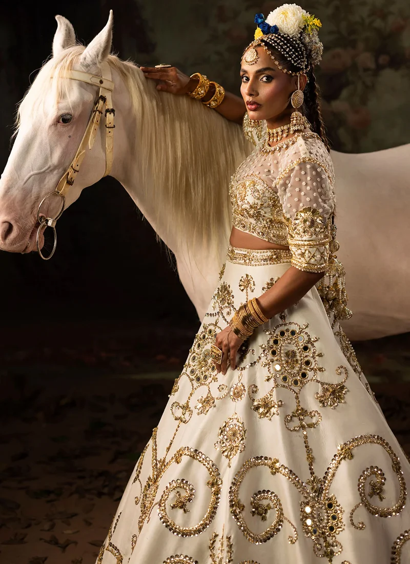 Ivory bridal lehenga choli full front view with a wide flared skirt and sweeping gold gota scrollwork