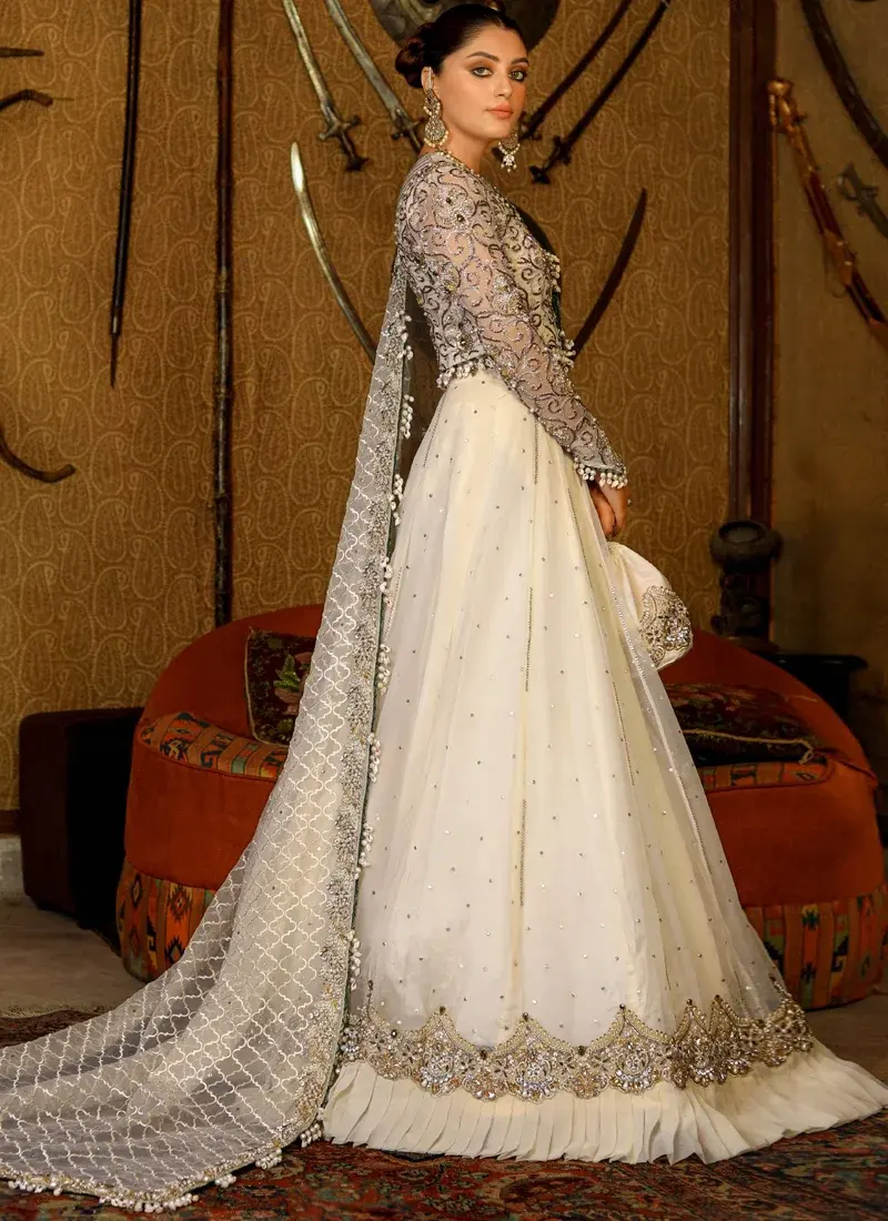 Ivory bridal choli front close-up with sheer round neckline, ornate scroll embroidery and pearl-tasselled waist