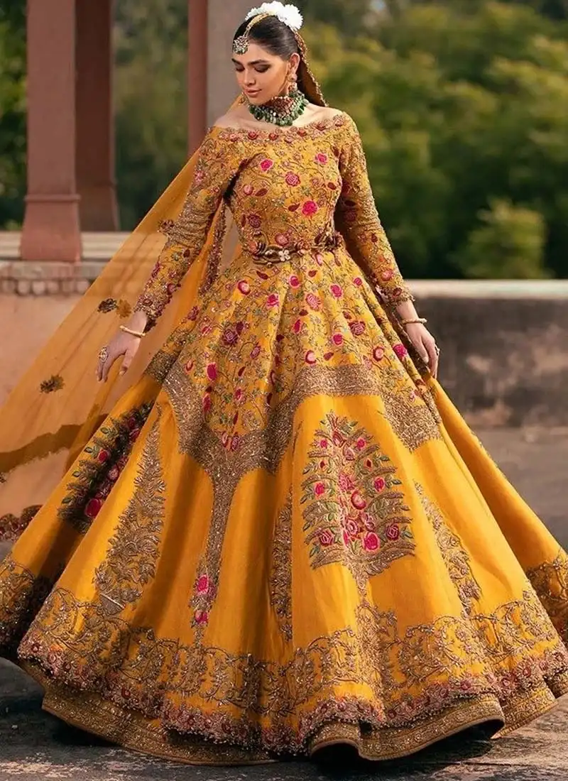 Mustard Mehndi Lehenga Choli with Floral Tree Motifs Mustard gold bridal lehenga front view with pink floral embroidery and tree motifs across the wide flared skirt